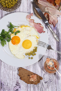 煎鸡蛋用新鲜欧芹和绿色的豌豆和烟熏肉