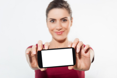 年轻女子显示移动手机与白色屏幕和微笑