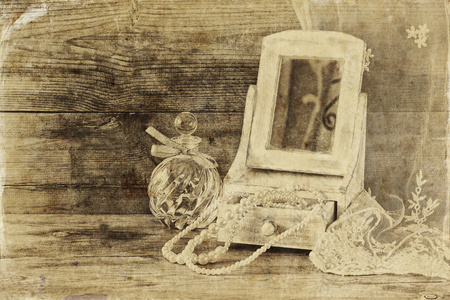 老式的珍珠，用木制的桌子上的镜子和香水瓶仿古木制首饰盒。黑色和白色的风格照片