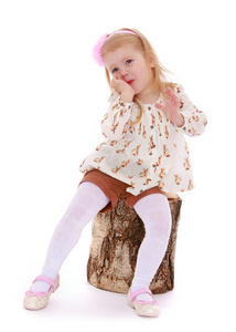 女孩坐在一个树桩上