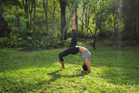 年轻女人做瑜伽练习中花园公园