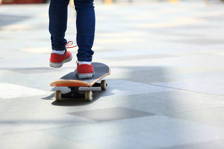 年轻的滑板腿骑在滑板上的城市