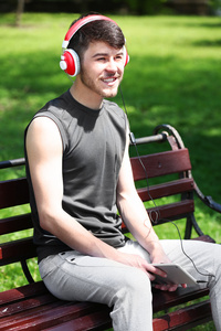 戴着耳机坐在公园长椅上休息的人