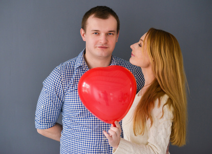美丽的夫妇，在情人节那天，在灰色的背景上用红色的气球心形爱