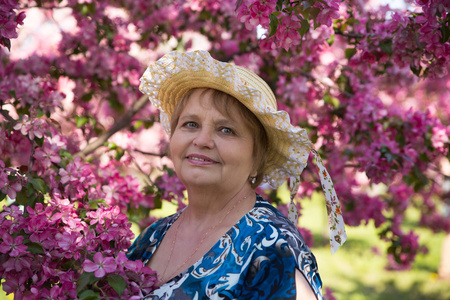 成年女性在粉红色的花树下的帽子