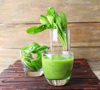 绿色健康汁菠菜和罗勒在桌上的玻璃关闭