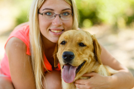 美丽的年轻女孩的肖像与她的狗拉布拉多猎犬户外在夏季美丽的公园