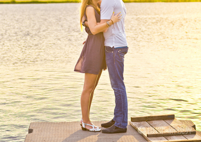 幸福的情侣拥抱而站在河岸边