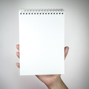 女人手拿着白色的空白笔记本