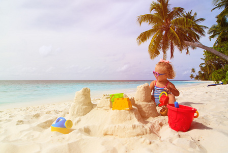 可爱的小女孩，在热带的海滩上玩沙子