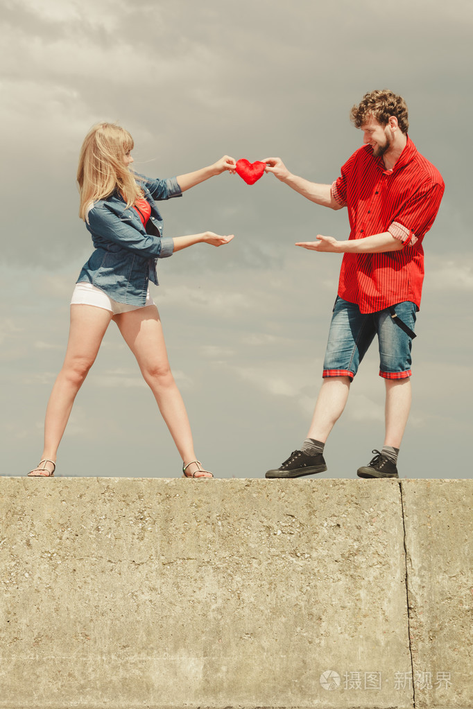 热恋中的情侣握着红色的心