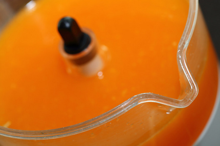 新鲜的橙汁在榨汁机用一只手
