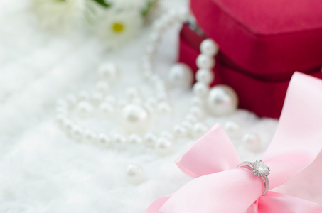 钻石戒指和珍珠项链上的粉红色丝带背景