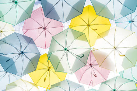 挂着五颜六色的雨伞，在街头和蓝色的天空。高键