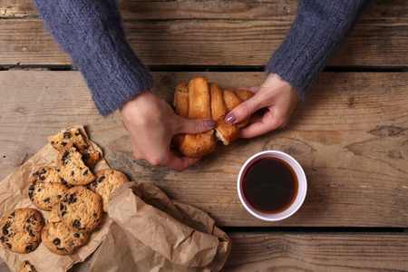 女性手里拿着杯咖啡和饼干木制的桌子上关闭