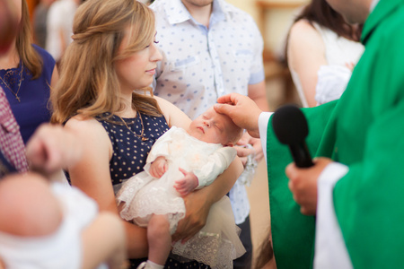 母亲的孩子在教堂洗礼仪式上抱着的小孩