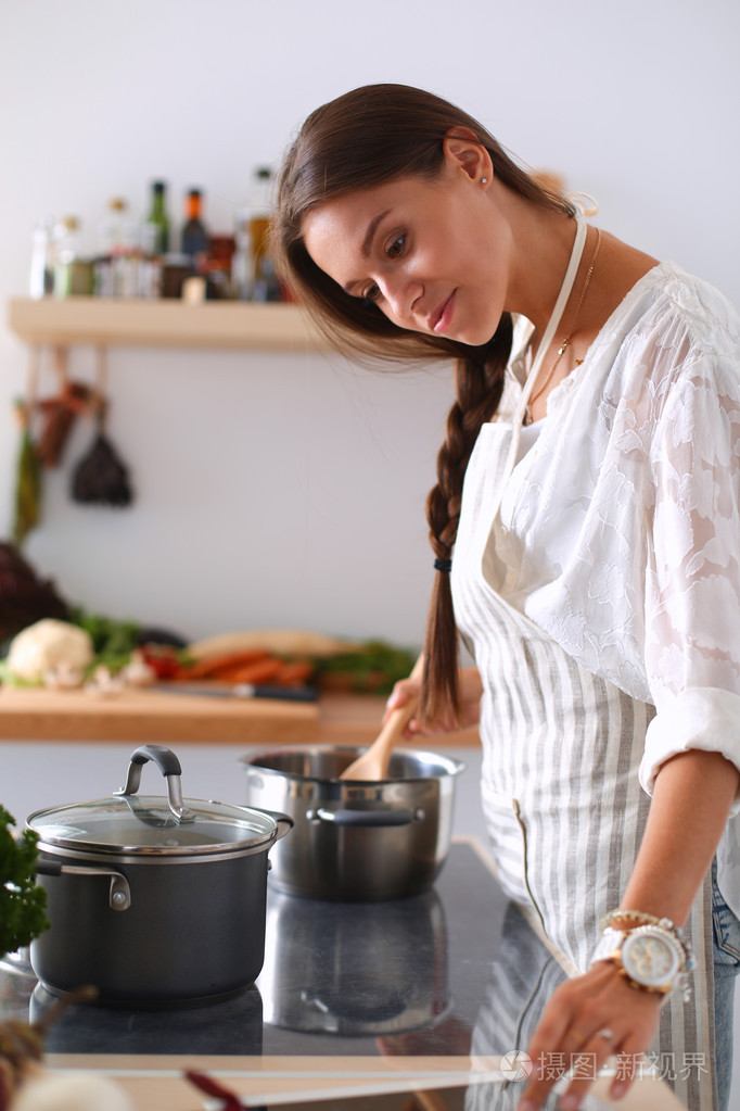 使用一台平板电脑,在她的厨房里做饭的年轻女人