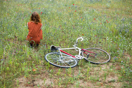 女人坐在草地上与自行车
