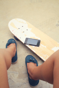 年轻的女孩，在滑板上的智能手机自拍照