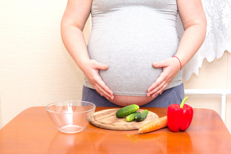 孕妇和桌子上的蔬菜。孕妇的饮食