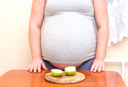 孕妇和桌上的绿色苹果切成薄片