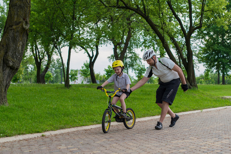 父亲和儿子学骑自行车在公园玩的乐趣