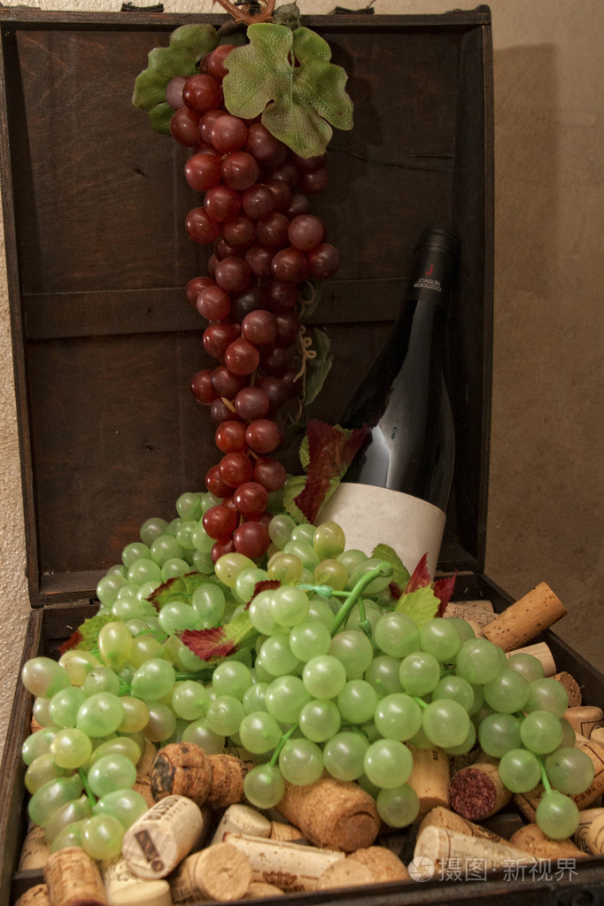 一瓶红葡萄酒与人工葡萄在盒子里充满了葡萄酒塞子