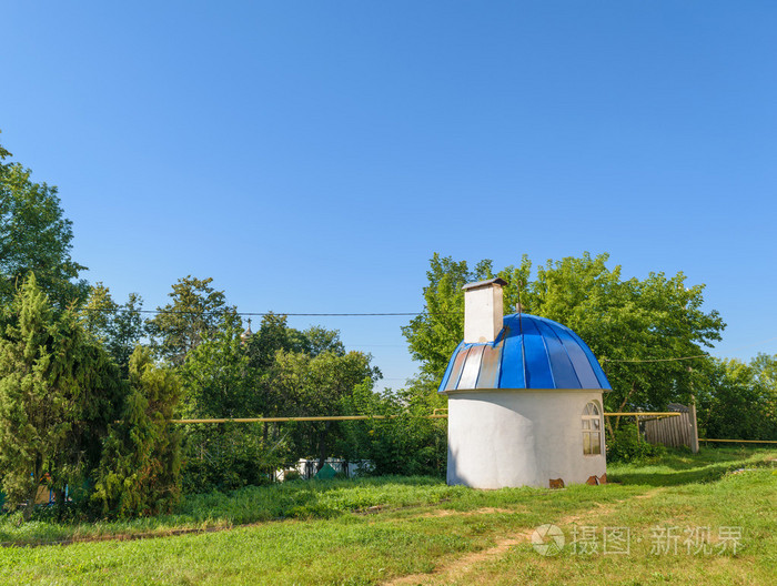 带有蓝色圆拱型屋顶上绿色的草坪上一天的小圆形房子