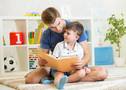 小男孩和他的父亲在家里的地板上看书