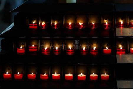 教堂里一大群在黑色背景下燃烧的蜡烛。