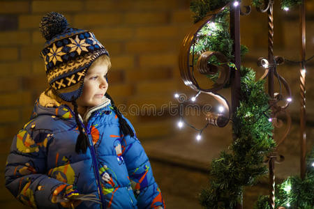 圣诞节时站在户外的可爱小男孩带着灯光