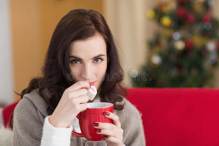 在圣诞节，黑发女人拿着杯子吃棉花糖