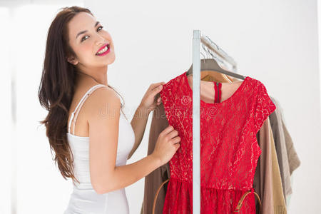 微笑着购物的黑发女人看着红裙子