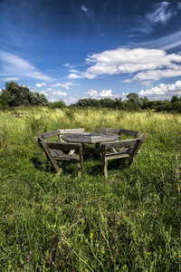 蓝天下草地上的乡村木制野餐椅