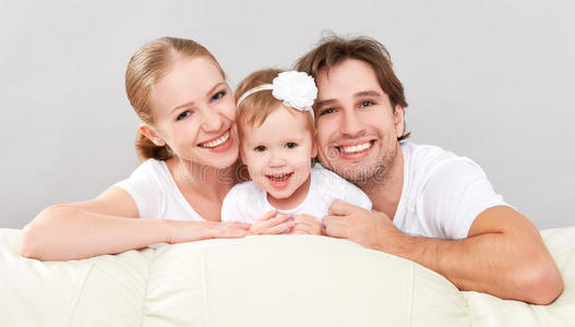 幸福的家庭母亲，父亲，孩子，女儿在家里的沙发上嬉笑