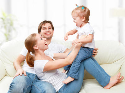 幸福的家庭母亲，父亲，孩子，女儿在家里的沙发上嬉笑