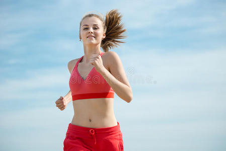 在阳光明媚的夏日沙滩上奔跑的年轻女士。训练。慢跑