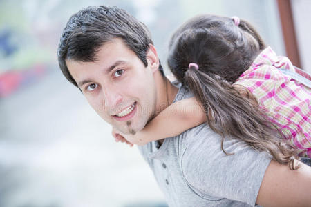 年轻人背着小女儿在家的侧视图