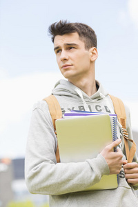 年轻的男大学生拿着书往外看
