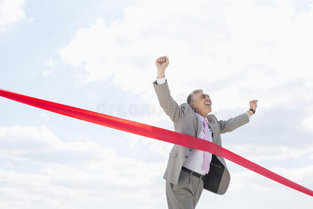 顶线增长兴高采烈的商人顶着天空越过终点线照片