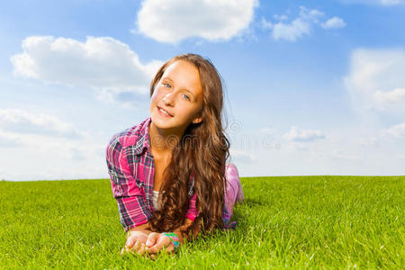 美丽的女孩躺在绿草上微笑着