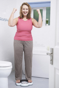 快乐的女人在浴室里称体重