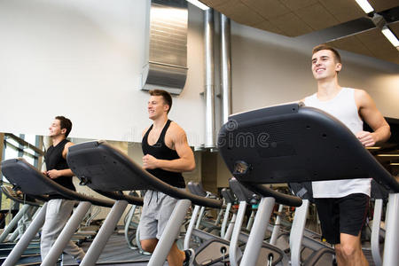 微笑的男人在健身房的跑步机上锻炼