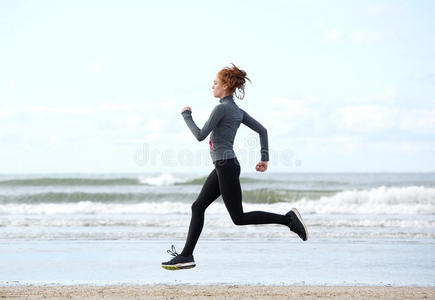 健康的年轻女子在沙滩上奔跑