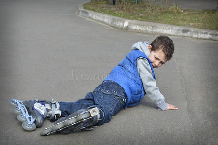 户外摔倒春天男孩滑旱冰,摔倒在路上.照片