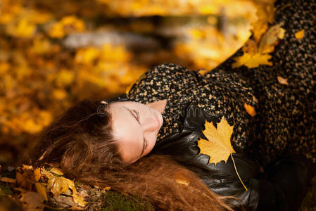 年轻漂亮的女人在秋天的公园里放松