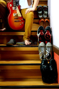 坐在楼梯上不同鞋子旁边拿着吉他的人