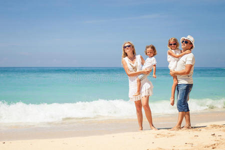 快乐的一家人白天在沙滩上散步。