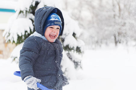 小男孩拿着铲子在雪地里玩