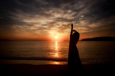 苗条的女孩,在这么长时间对海上日出的剪影照片